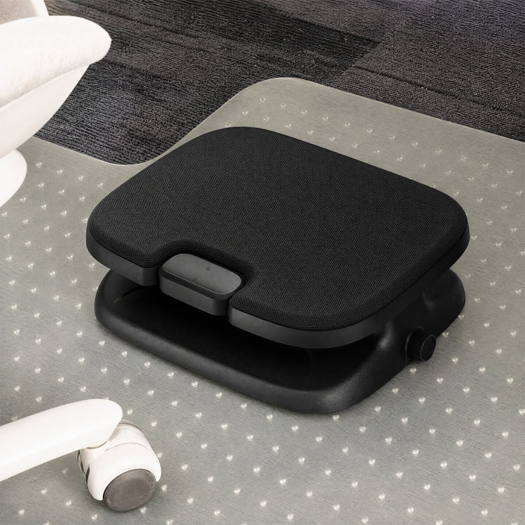 A black ergonomic footrest with a textured fabric top and adjustable base