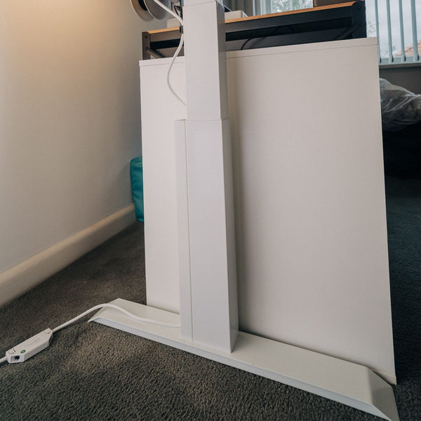 White magentic cable management attached to white standing desk frame