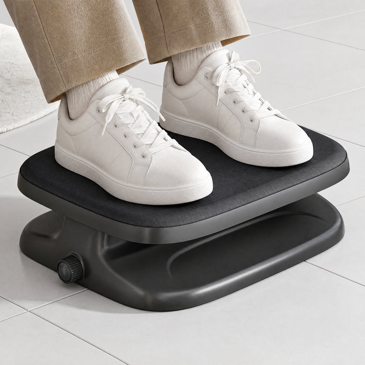A person wearing beige pants and white sneakers stands on a black step platform with a small adjustment knob, set on a light gray tiled floor.