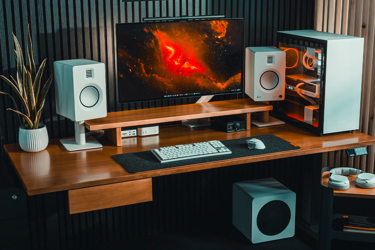 Desky Dual Hardwood Sit Stand Desk in White Oak with Minimal Under Desk Drawer, Minimal Monitor Stand and Integrated Cable and Power Channel in a dark studio